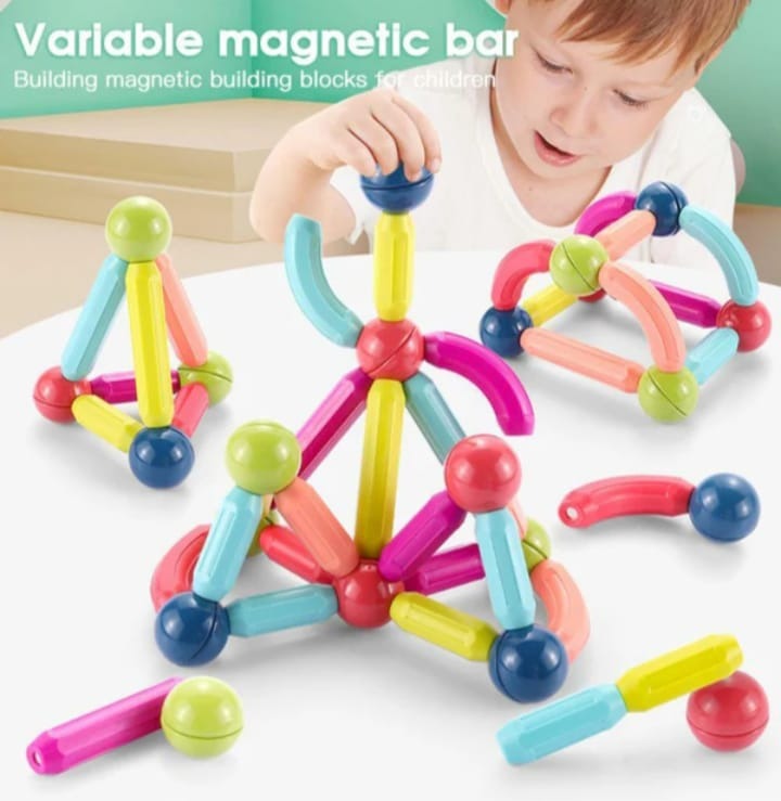 Colorful magnetic building blocks with a child playing with them on a white surface.