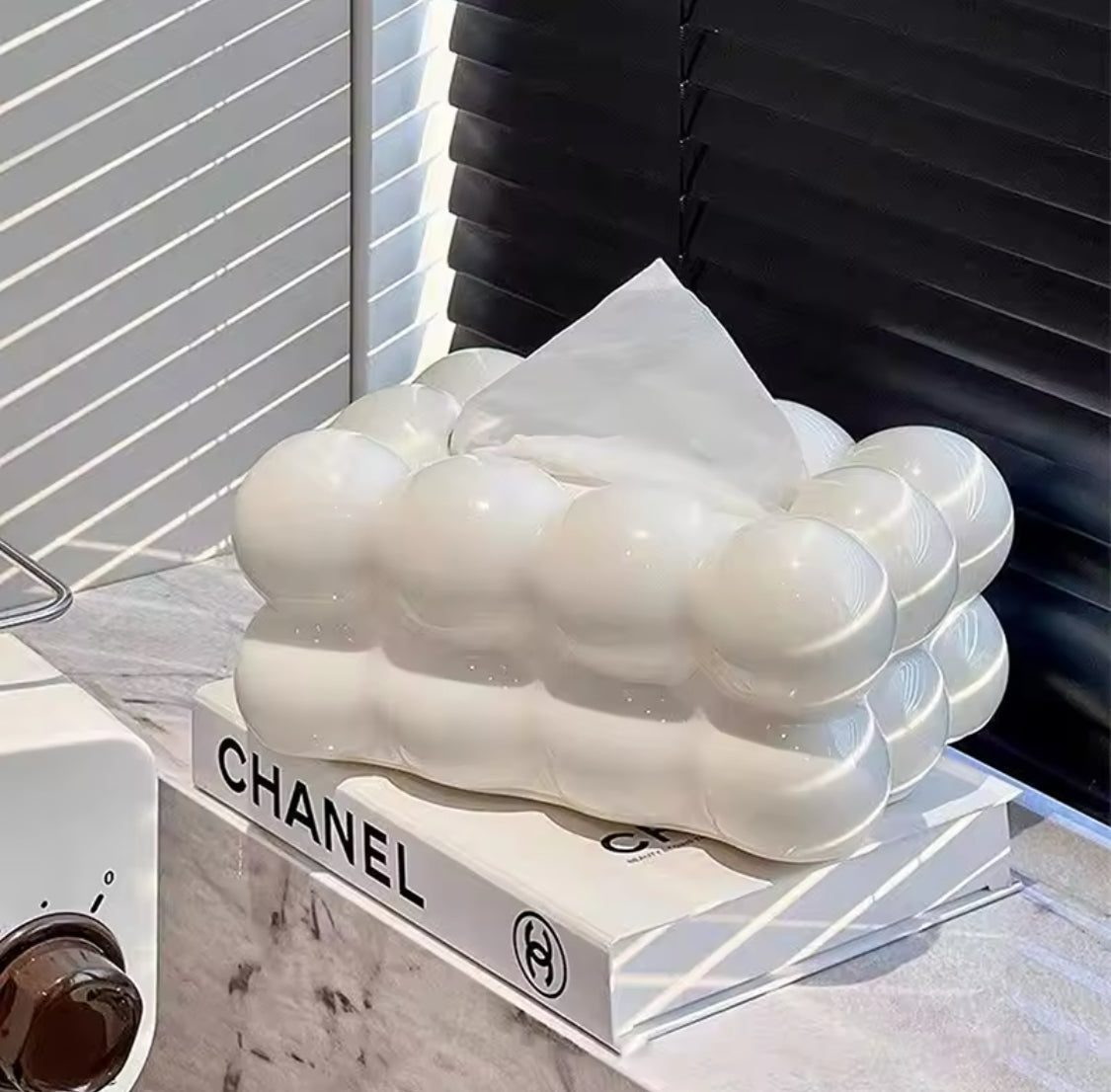 White sculpture resembling feet on a Chanel book with a blurred background