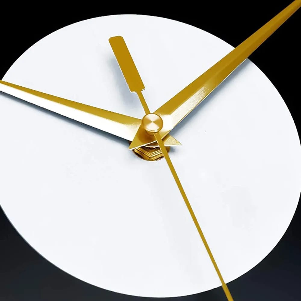 Close-up of a clock with gold hands on a white face against a black background