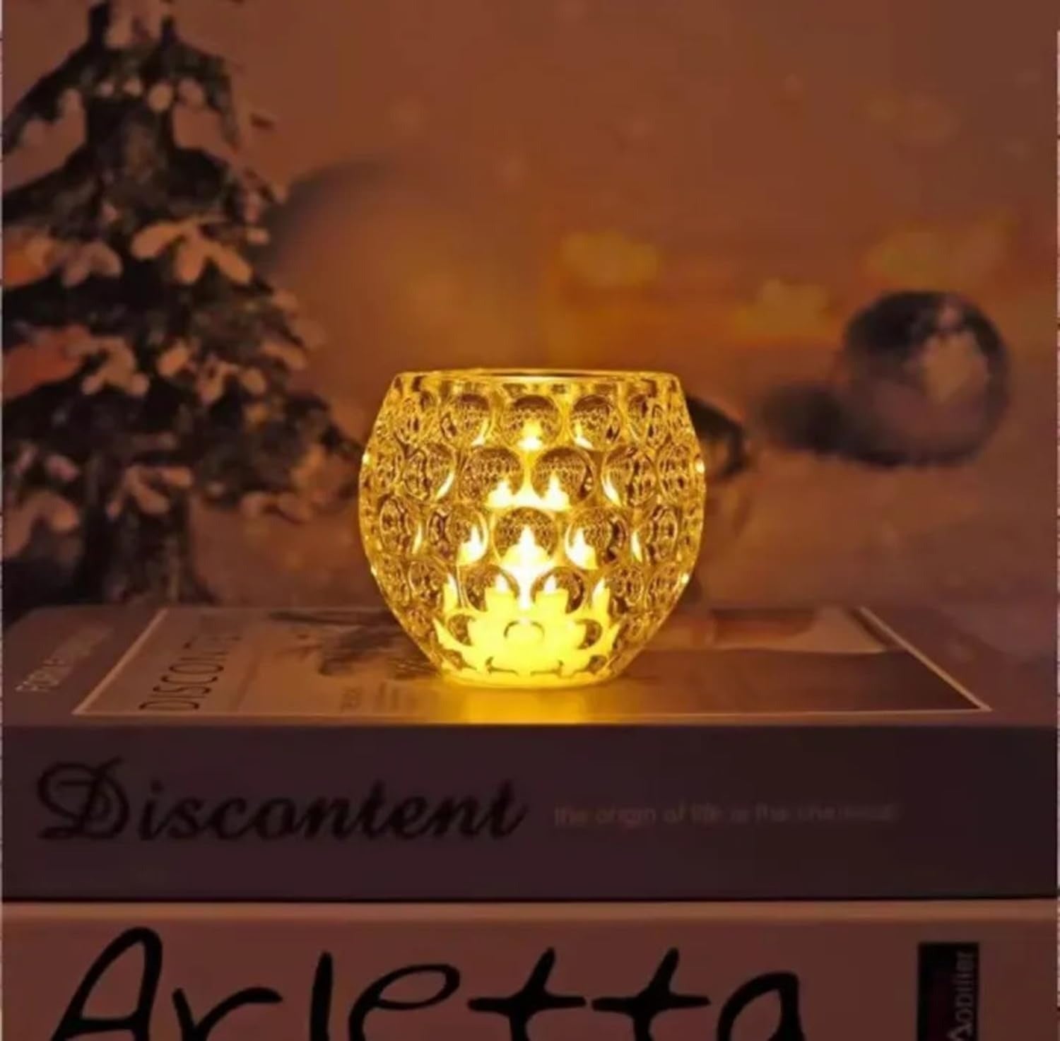 Decorative candle holder on a book with a blurred Christmas tree in the background