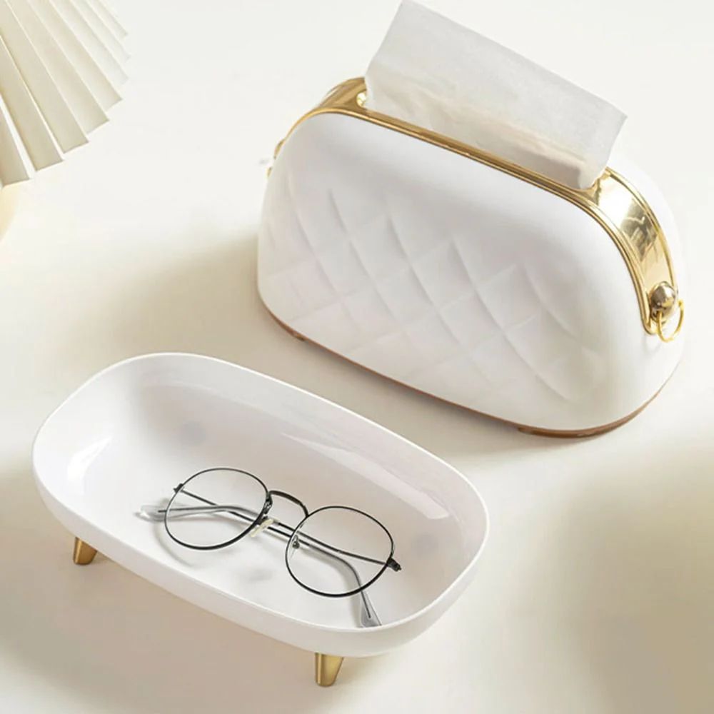 White eyeglass case with gold accents and a pair of glasses on a light background