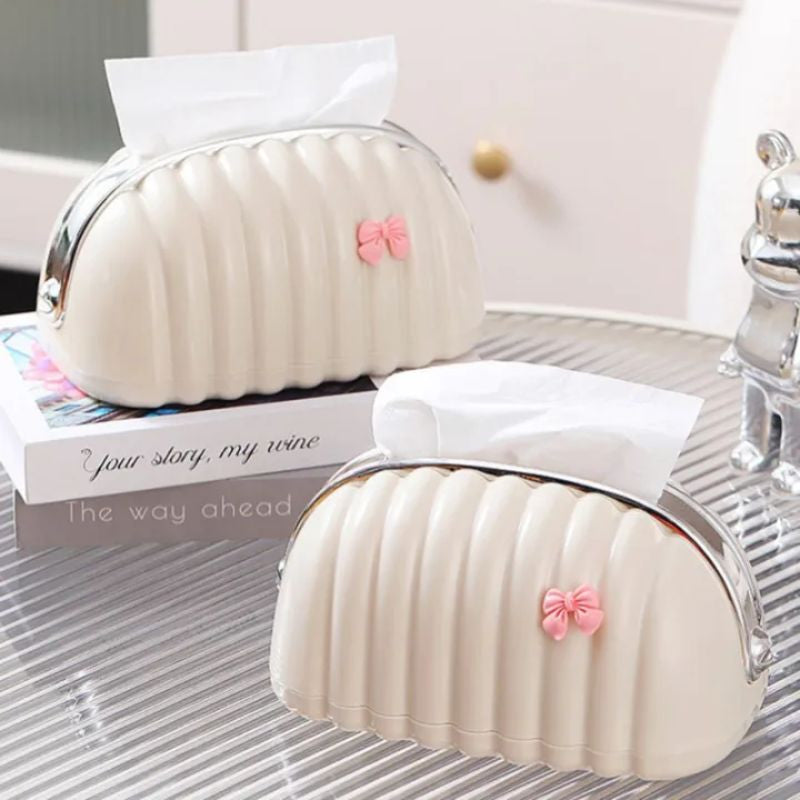 Two white pumpkin-shaped tissue holders with pink bows on a glass surface.