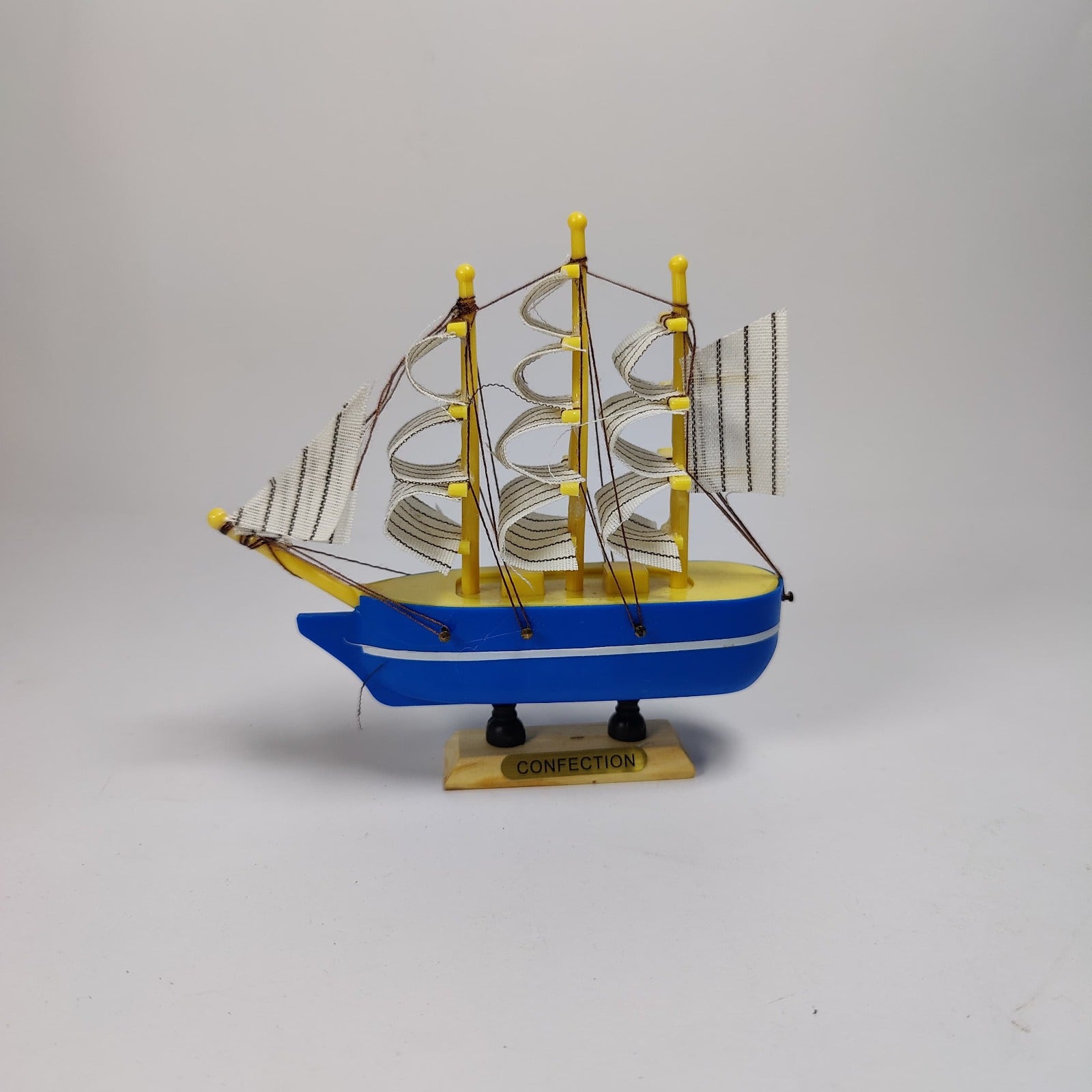 Model ship with blue hull and yellow masts on a gray background