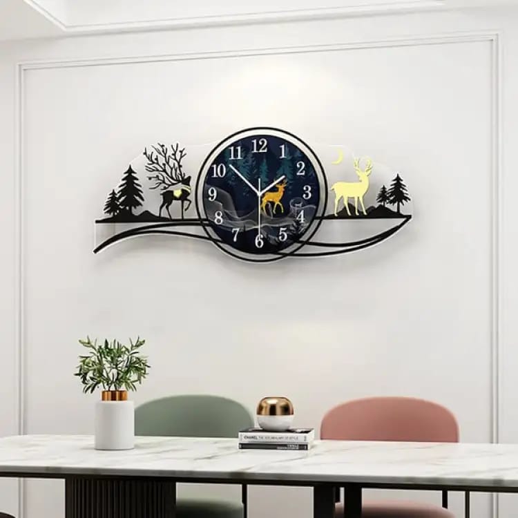 Decorative wall clock with deer and tree design on a white wall above a table.
